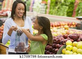 Woman and daughter shopping for apples at a grocery store Woman and daughter shopping for apples at a grocery store