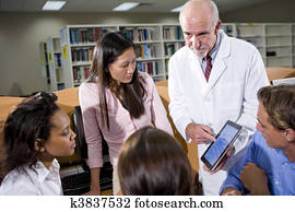 College students with teacher talking in library