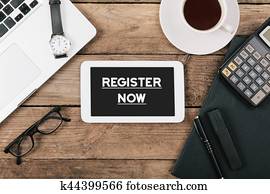 Register Now text on tablet computer on office desk Register Now text on tablet computer on office desk