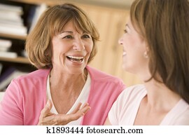 Two women sitting in living room talking and smiling Two women sitting in living room talking and smiling