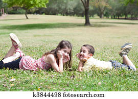 Cute children lie down on green grass