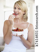 Mid Adult Woman Eating A Bowl Of Strawberries
