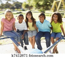 Group Of Children Riding On Roundabout In Playground Group Of Children Riding On Roundabout In Playground