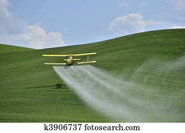 Biplane Crop Duster spraying a farm field. Biplane Crop Duster spraying a farm field.
