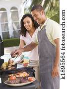 Couple Cooking On A Barbeque Couple Cooking On A Barbeque