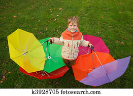 Boy in autumn park, in environment of multi-coloured umbrellas. Top view. Horizontal format.