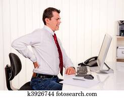 Man in office with computer and back pain Man in office with computer and back pain