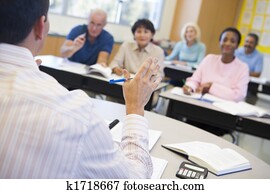 Teacher in class lecturing adult students (selective focus) Teacher in class lecturing adult students (selective focus)