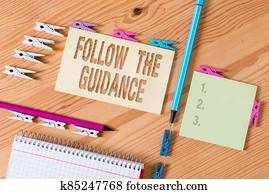 Writing note showing Follow The Guidance. Business photo showcasing controlling a course of projectile by builtin mechanism Colored clothespin papers empty reminder wooden floor background office.