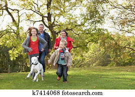 Young Family Outdoors Walking Through Park With Dog Young Family Outdoors Walking Through Park With Dog
