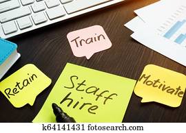 Staff hire, train, motivate and retain written on a memo sticks. Staff hire, train, motivate and retain written on a memo sticks.