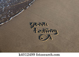 Gone fishing written in the sand at the beach with a small wave lapping at the edge of the scene.