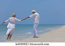 Happy Senior Couple Dancing Holding Hands on A Tropical Beach