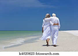 Rear View of Senior Couple Walking Alone on A Tropical Beach