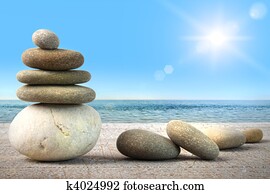 Stack of spa rocks on wood against blue sky