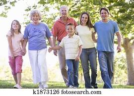 Extended family walking in park holding hands and smiling