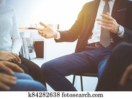 Group of people sitting in a circle during therapy in sunny office. Meeting of business team participating in training Group of people sitting in a circle during therapy in sunny office. Meeting of business team participating in training