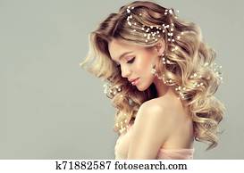 Pretty woman with soft smile on the face is demonstrating long and curly hairstyle. Pretty woman with soft smile on the face is demonstrating long and curly hairstyle.