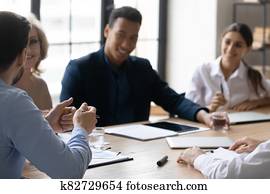 Interested diverse employees listening to mentor coach at meeting Interested diverse employees listening to mentor coach at meeting