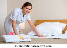 Maid making bed in hotel room Maid making bed in hotel room