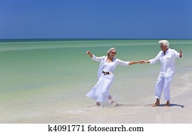 Happy Senior Couple Dancing Holding Hands on A Tropical Beach