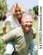 Senior man giving piggy ride to her wife Senior man giving piggy ride to her wife