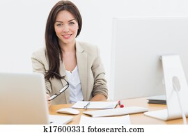 Young woman with computers at desk in office