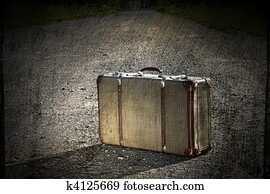 Old suitcase left on a dirt road
