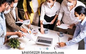 Working late night of Interracial business team wear face mask brainstorm at new normal office