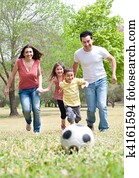 Parents and two young children playing soccer in the green field, outdoor