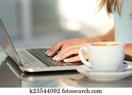 Woman hands typing in a laptop in a coffee shop