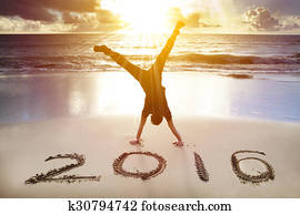 happy new year 2016. young man handstand on the beach