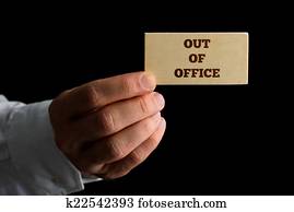 Man with a business card reading - Out of Office