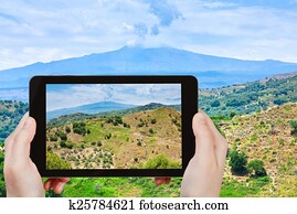 tourist taking photo of rural landscape with Etna