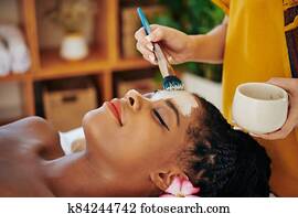 Woman geting purifying clay mask Woman geting purifying clay mask