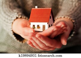 Woman holding a small new house in her hands. Real estate, mortgage