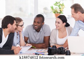 Friendly office discussion. Group of cheerful business people sitting together at the table and discussing something