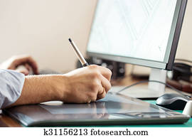 Graphic designer using digital tablet and computer in office or home Graphic designer using digital tablet and computer in office or home