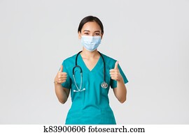 Covid-19, coronavirus disease, healthcare workers concept. Confident, smiling asian doctor, female nurse in scrubs and medical mask profive good quality service, show thumbs-up in approval Covid-19, coronavirus disease, healthcare workers concept. Confident, smiling asian doctor, female nurse in scrubs and medical mask profive good quality service, show thumbs-up in approval