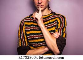 Young woman gesturing hush with her finger on her lip