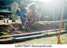 Carefree barefoot girl on swing in sun light