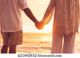Senior Couple Holding Hands Enjoying at Sunset