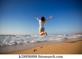 Happy woman jumping at the beach