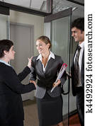 Office workers shaking hands at door of boardroom