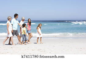 Three Generation Family Walking Along Sandy Beach