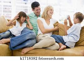 Family sitting in living room with digital camera smiling