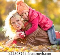 Parent and child lying together on falling leaves. Family outdoo Parent and child lying together on falling leaves. Family outdoo