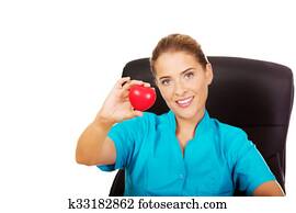 Young female doctor holding toy heart