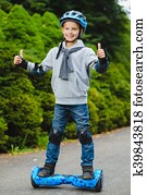 Happy boy standing on hoverboard or gyroscooter outdoor