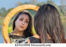 Woman looking at mirror in nature
